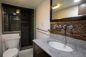 Bathroom with vanity, toilet, and tiled shower