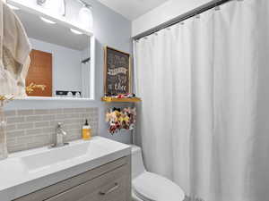 Bathroom with vanity, tasteful backsplash, and toilet