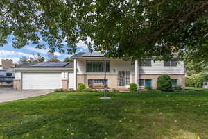 View of front of property featuring solar panels, a garage, and a front yard