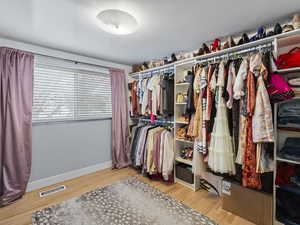 Walk in closet with light hardwood / wood-style floors