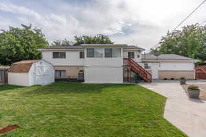 View of front facade with a patio area, a front lawn, central AC unit, and a storage shed