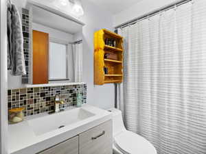 Bathroom featuring vanity, backsplash, and toilet