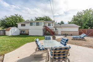 Rear view of house featuring a lawn, a patio area, and a shed