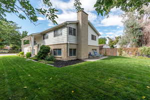 Rear view of house with a patio area and a yard