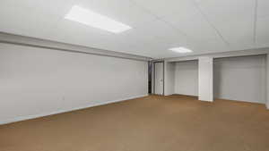 Basement featuring a paneled ceiling and carpet