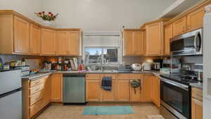 Kitchen with light tile patterned floors, sink, appliances with stainless steel finishes, and tasteful backsplash