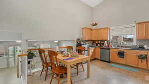 Kitchen with stainless steel dishwasher, decorative backsplash, sink, and high vaulted ceiling