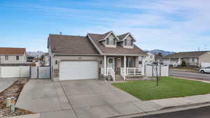 View of front of property with a mountain view, a front lawn, covered porch, and a garage