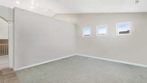 Carpeted spare room with lofted ceiling and a wealth of natural light