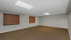 Unfurnished room featuring a paneled ceiling and dark carpet