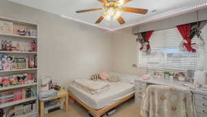 Bedroom with ceiling fan and light carpet