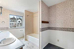 Bathroom featuring tile patterned floors, vanity, and tiled shower / bath