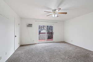 Spare room with carpet floors, a wall unit AC, and ceiling fan