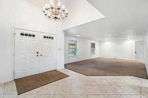 Foyer with a chandelier and light colored carpet