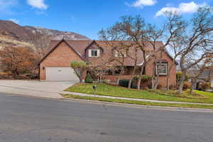 View of front of property featuring a mountain view, a front yard, and a garage