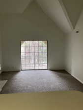 Carpeted spare room featuring high vaulted ceiling