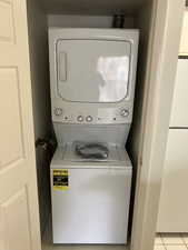 Laundry area with light tile patterned floors and stacked washing maching and dryer