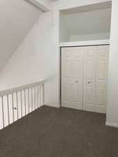 Unfurnished bedroom with carpet, vaulted ceiling with beams, and a closet