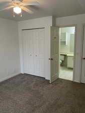 Unfurnished bedroom with a closet, ceiling fan, ensuite bathroom, and light carpet