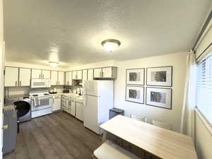 Kitchen with white appliances, dark wood-type flooring, sink, a textured ceiling, and washer / clothes dryer