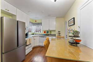 Kitchen with white cabinetry, dark hardwood / wood-style flooring, white appliances, and sink