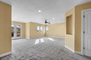 Carpeted empty room with ceiling fan, a textured ceiling, and french doors