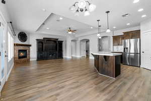 Kitchen featuring a kitchen bar, stainless steel fridge, wood-type flooring, pendant lighting, and an island with sink