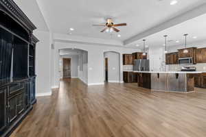 Kitchen featuring a textured ceiling, stainless steel appliances, a spacious island, decorative light fixtures, and hardwood / wood-style flooring