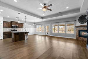 Kitchen with pendant lighting, dark hardwood / wood-style flooring, stainless steel appliances, and a center island with sink