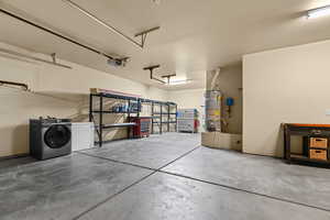 Garage with white fridge, strapped water heater, a garage door opener, and washing machine and clothes dryer