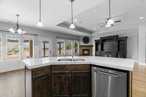 Kitchen with dishwasher, sink, an island with sink, pendant lighting, and light wood-type flooring