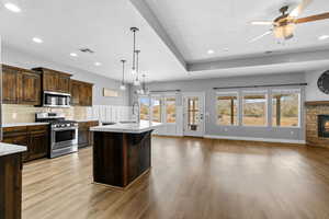 Kitchen with a wealth of natural light, a kitchen island with sink, stainless steel appliances, and light hardwood / wood-style floors