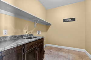 Washroom featuring cabinets, hookup for a washing machine, light tile patterned floors, and sink