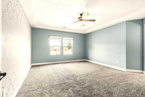 Carpeted empty room featuring ceiling fan and a textured ceiling