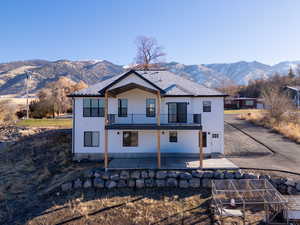 Rear view of property featuring a mountain view, a patio area, and a balcony