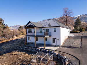 Rear view of property featuring a mountain view, a balcony, and a patio