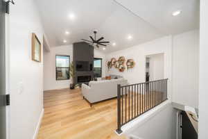 Living room featuring light LVP flooring, ceiling fan, and lofted ceiling