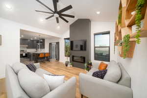 Living room featuring ceiling fan, lofted ceiling, and light LVP flooring