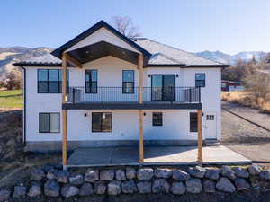 Rear view of house featuring a mountain view, a balcony, and a patio