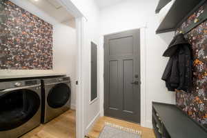 Clothes washing area with washer and dryer and light LVP flooring