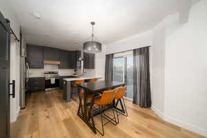 Kitchen featuring a kitchen bar, a barn door, stainless steel appliances, and light LVP flooring