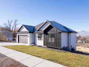 View of front of home with a mountain view, a front lawn, and a garage