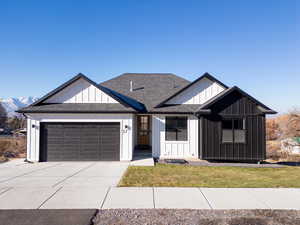 View of front of house with a mountain view, a garage, and a front lawn