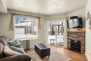 Living room featuring a fireplace, a textured ceiling, light wood-type flooring, and plenty of natural light