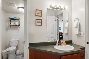 Bathroom with vanity, toilet, and a textured ceiling