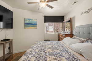 Bedroom with a textured ceiling, light hardwood / wood-style flooring, and ceiling fan