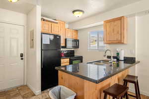 Kitchen featuring a breakfast bar area, kitchen peninsula, sink, and black appliances