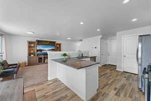 Kitchen featuring sink, white cabinetry, wood-type flooring, kitchen peninsula, and stainless steel appliances