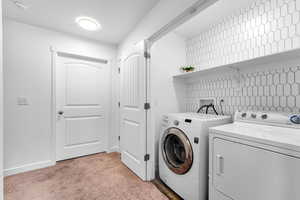 Laundry area with separate washer and dryer and light carpet