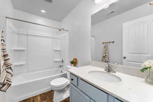 Full bathroom with hardwood / wood-style floors, vanity, toilet, and shower / bath combination